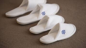 Un par de pantuflas blancas con bordados azules sobre un suelo alfombrado.