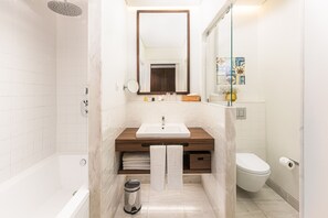 A modern bathroom with a bathtub, a sink with a wooden countertop, a mirror, and a toilet. - Corpo Santo Lisbon Historical Hotel (Lisbon)