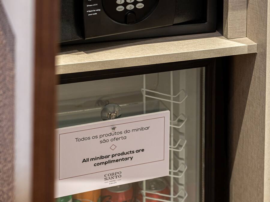 Een minibars kastje met een Coca-Cola en Fanta koelapparaat, een minibardeurtje en een bedieningspaneel voor de minibar.
