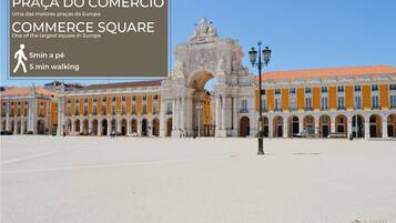 A large open square with historic buildings, a prominent archway, and a statue.