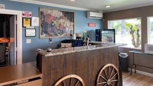 A reception area with a wooden counter, a large abstract painting, and a Coca-Cola sign.