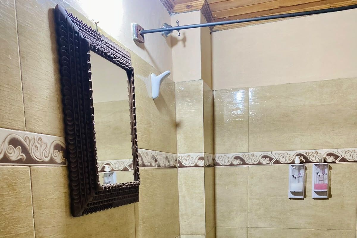 A bathroom with a wooden vanity, a mirror, a towel rack, and a shower area.