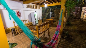 An outdoor patio with wooden furniture, a hammock, and a refrigerator. - Posada los Tajibos (Puerto Iguazú)