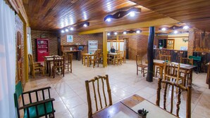 A restaurant with wooden tables and chairs, brick walls, and a tiled floor. - Posada los Tajibos (Puerto Iguazú)