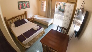 A room with two beds, a wooden table, a TV, and a door leading outside. - Posada los Tajibos (Puerto Iguazú)
