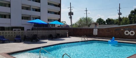 A rectangular swimming pool with two ladders, surrounded by a tiled deck.