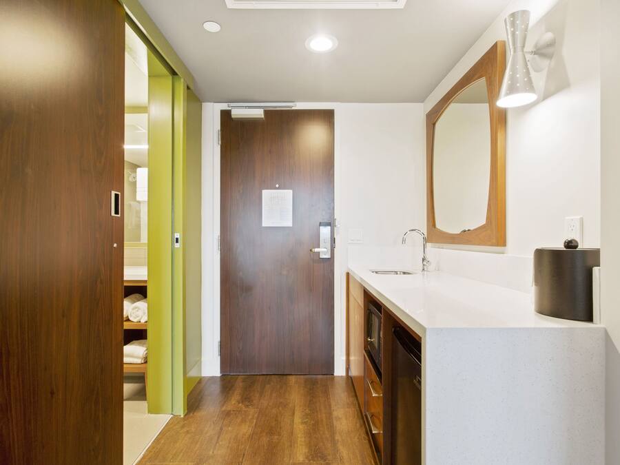 A modern bathroom with a wooden door, a white sink, and a mirror.