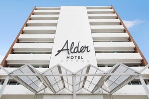The exterior of the Alder Hotel Uptown, featuring a prominent sign with the hotel's name and a modern architectural design with a glass facade.