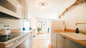 Een moderne keuken met een magnetron, fornuis en spoelbak. Er is een houten aanrecht en kastjes. Een plant is zichtbaar op de achtergrond.