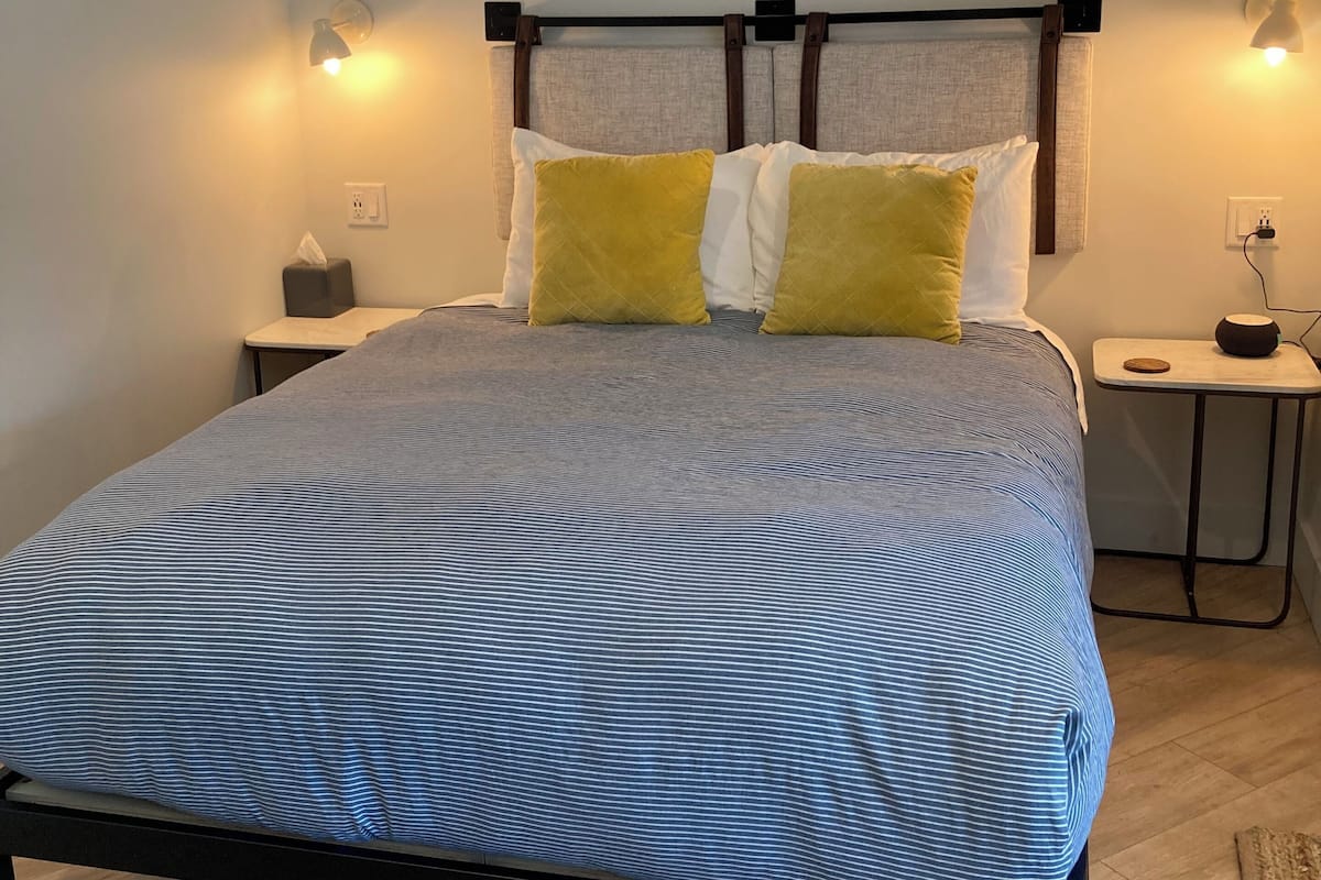 Ein Schlafzimmer mit einem Bett, zwei Nachttischlampen, einem Nachttisch und einem Kopfteil.