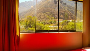 A room with a large window offering a view of a mountainous landscape. - Tambo de Ollantay (Ollantaytambo)
