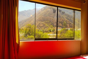 Una habitación con un amplio ventanal que ofrece vistas a un paisaje montañoso.