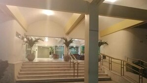 Un vestíbulo amplio con una imponente escalera, una zona de recepción y un gran jarrón decorativo.