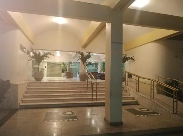 A spacious lobby with a grand staircase, a reception area, and a large decorative vase.