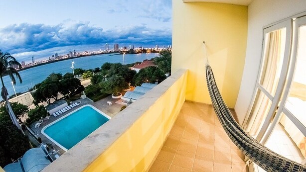 Un balcón con vista a un paisaje urbano y una piscina.