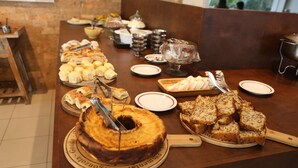 Una mesa de buffet con diversos alimentos, incluyendo un pastel grande, pan y repostería.