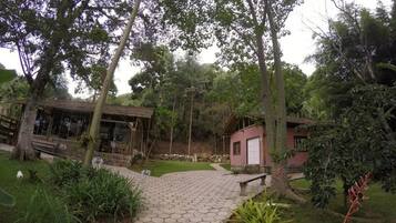 Un sendero en un jardín que conduce a un edificio con fachada de vidrio y una pequeña estructura roja.