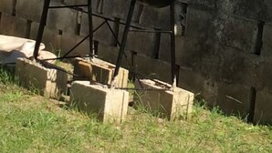A barbecue grill with a black top and a brown seat, placed on a concrete base with a brick wall in the background. - MaFlo Arms Apartments (Belize City)