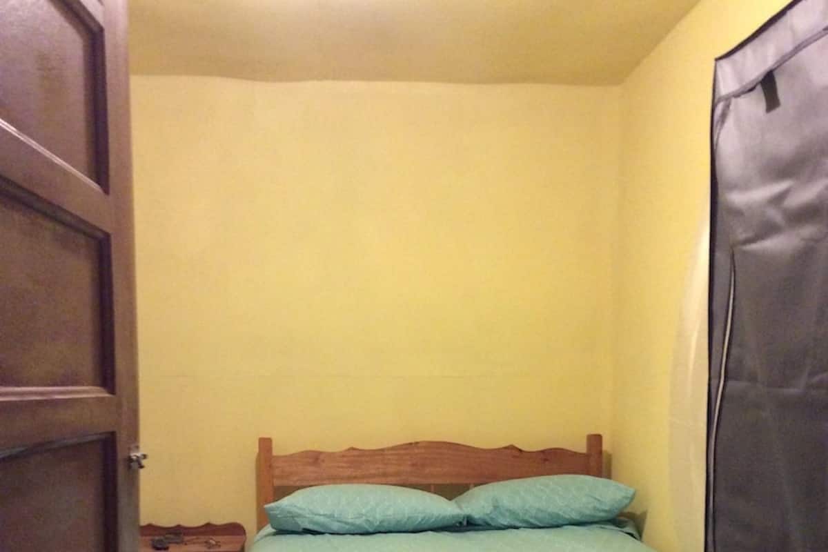 A small bedroom with a bed, wooden headboard, and a nightstand.
