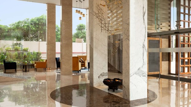 Eine großzügige Lobby mit Marmorsäulen, einer zentralen Sitzecke und Blick ins Freie.