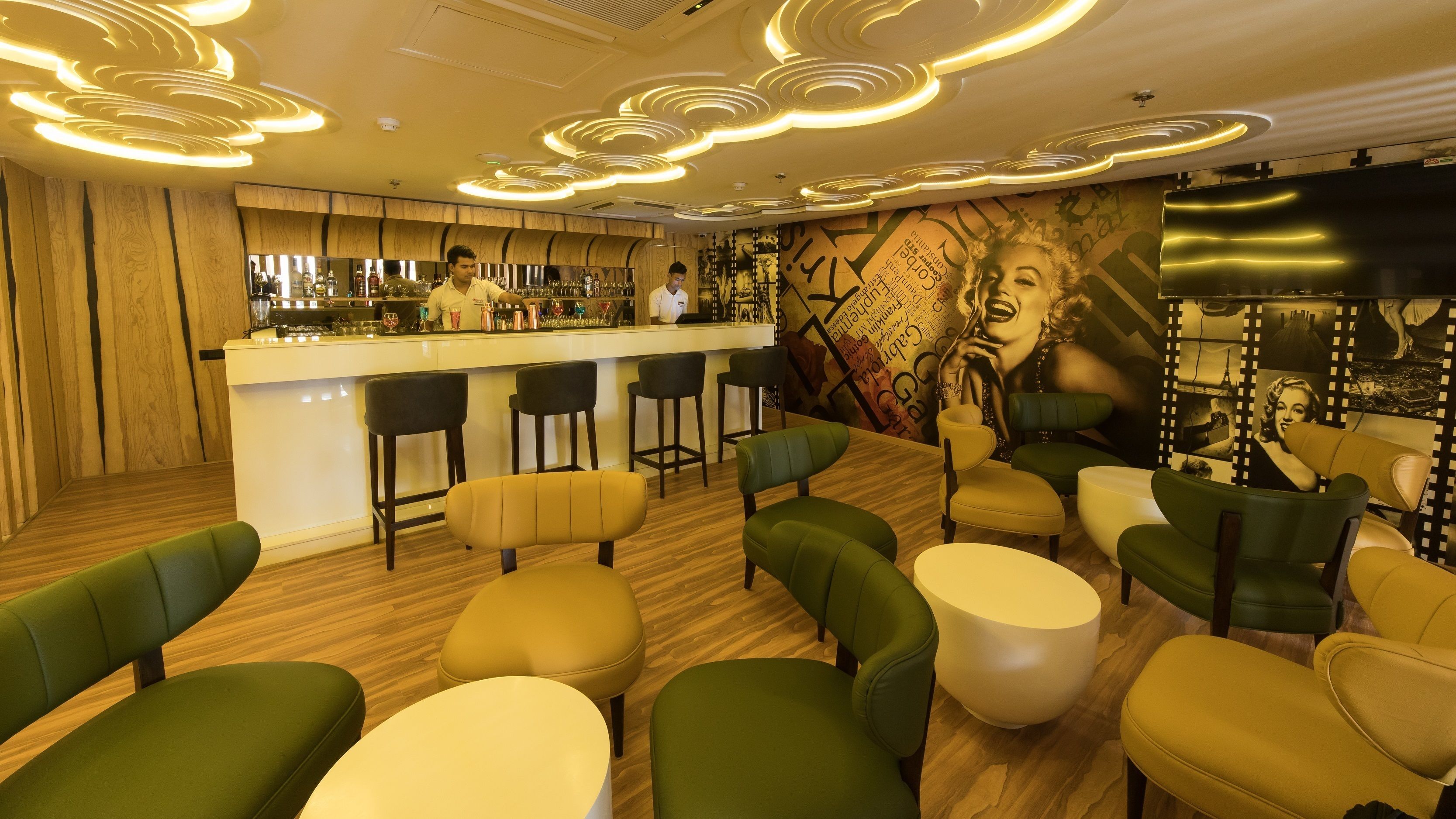 A bar area with a wooden bar counter, stools, and a mural on the wall.