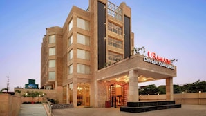 Ein modernes Hotel mit markantem Eingang, mehreren Stockwerken und einer Schilder mit dem Namen und der Adresse.