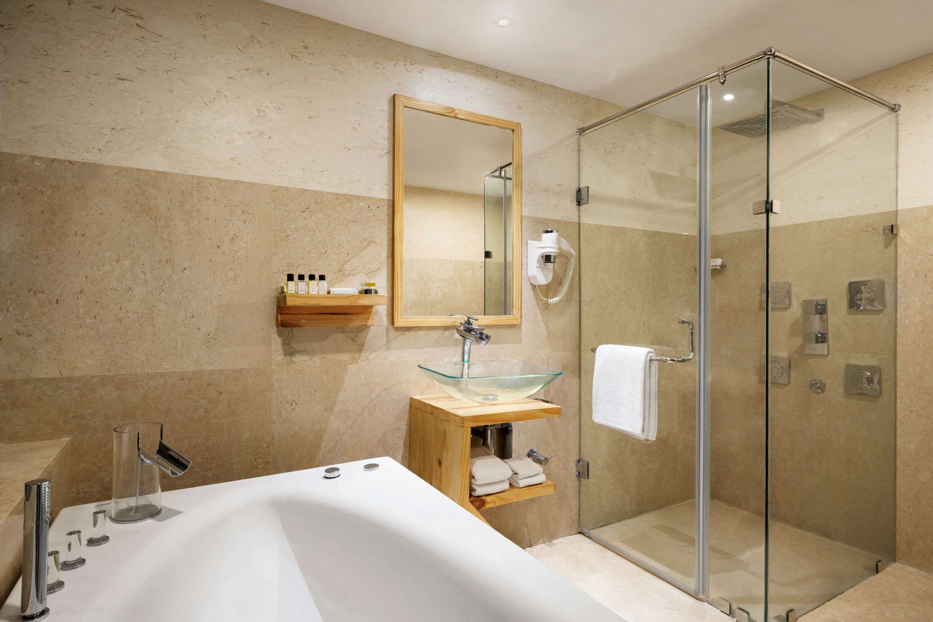A modern bathroom with a glass-enclosed shower, a freestanding bathtub, and a wooden vanity with a glass sink.