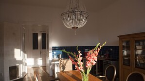 Eine Küche mit Holztisch, Stühlen, einer Blumenvase, einem Kronleuchter und einer blauen, gefliesten Rückwand.