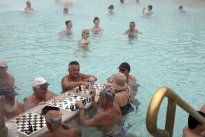 Un groupe de personnes jouant aux échecs au bord d’une piscine.