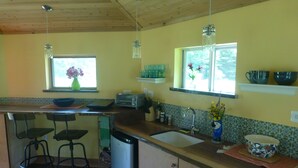 A kitchen with a wooden ceiling, a window with a flower vase, a sink, a toaster, and a refrigerator. - Cozy, Artistic Retreat Surrounded By Waterfalls, Orchards And Gardens (Newfield)