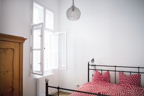 Ein Schlafzimmer mit einem Bett, einem Holzschrank und einem Fenster mit geöffneten Fensterläden.
