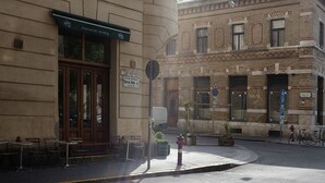 Vista da rua com um edifício com toldo verde e um letreiro indicando um restaurante chamado "Bares Beli".