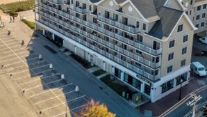 A multi-story hotel with a central courtyard, a parking lot, and a view of the sea. - Crashing surf, steps to the sand, Pier BEST CONDO IN OLD ORCHARD BEACH (Old Orchard Beach)