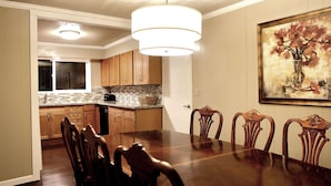 A dining room with a wooden table and chairs, a chandelier, and a painting on the wall.