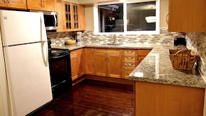 A kitchen with wooden cabinets, a white refrigerator, a microwave, a sink, and a window.