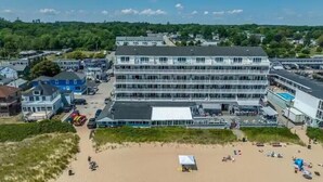 Un hotel de varios pisos con un patio central, rodeado de playa y vegetación.
