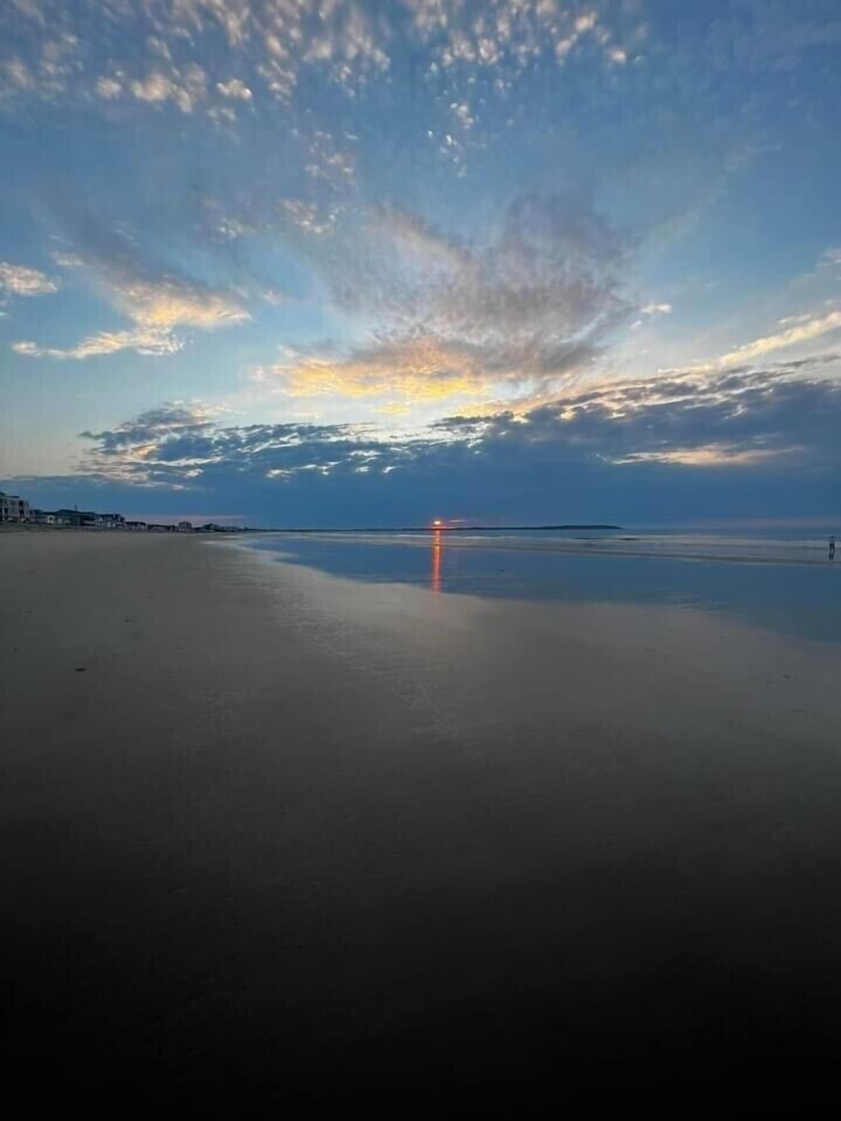 Une plage avec une mer calme et un coucher de soleil.