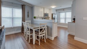 Una cocina moderna con armarios blancos, una isla central con asientos y un microondas encima.