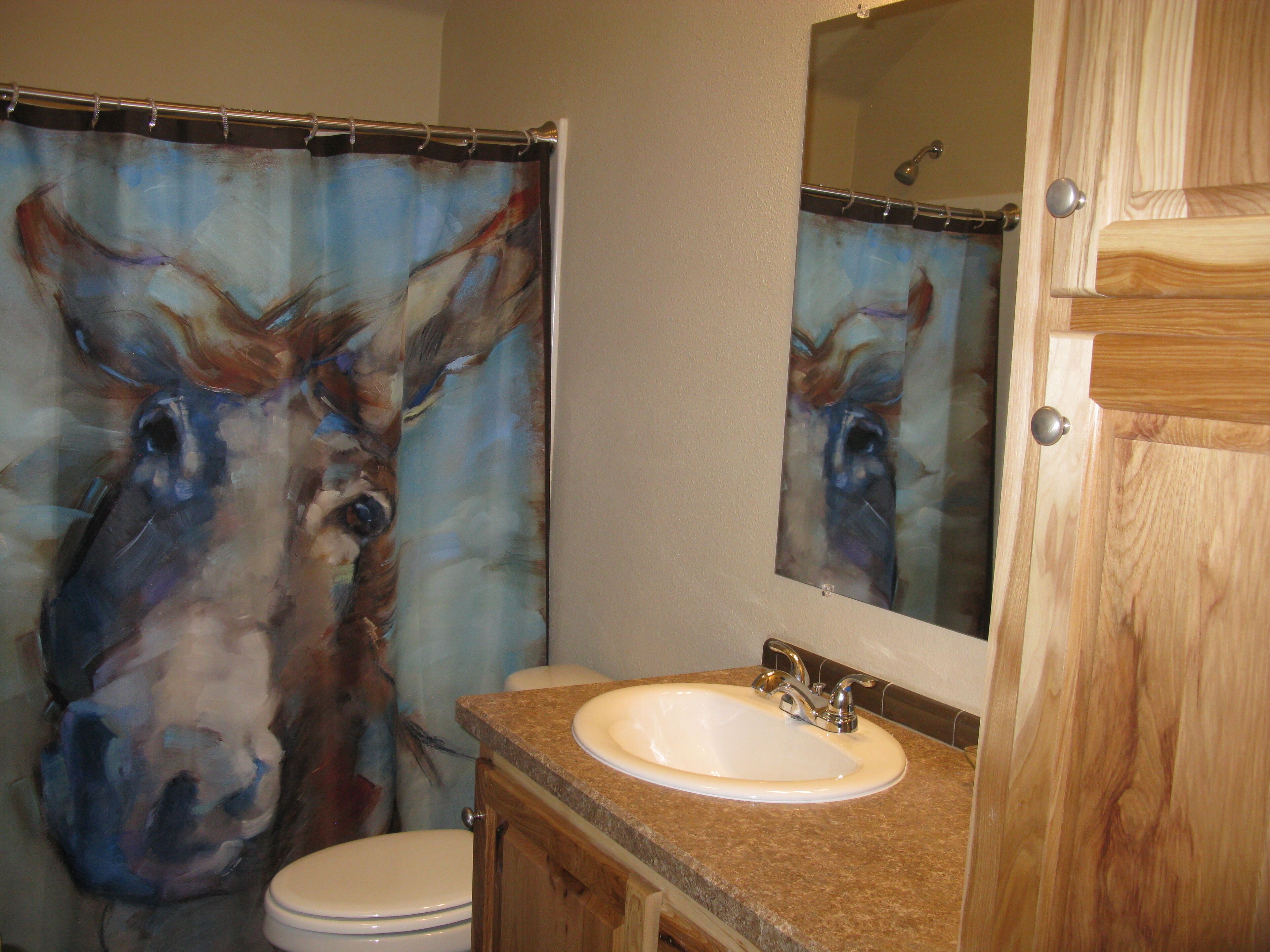 Un baño con tocador de madera, lavamanos y espejo.