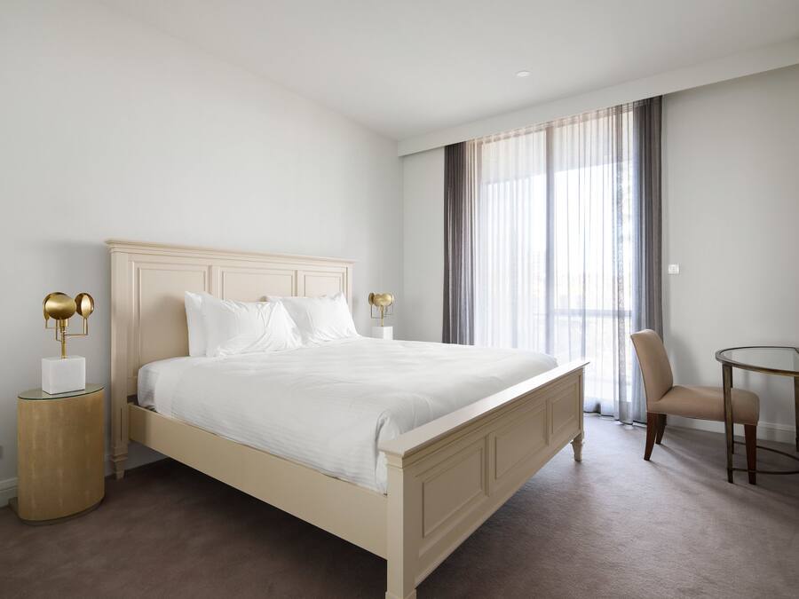 A bedroom with a bed, bedside tables, a chair, and a TV.
