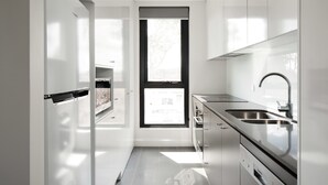 A modern kitchen with a large window, stainless steel appliances, and white cabinetry. - Knightsbridge Canberra (Kingston)