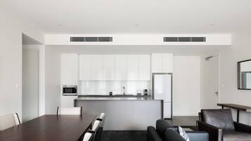 A modern kitchen with white cabinets, a central island, and a microwave.