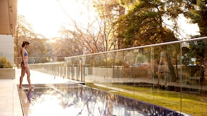 A glass railing overlooking a reflective pool with trees in the background. - Knightsbridge Canberra (Kingston)