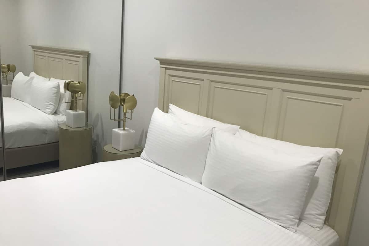Una habitación de hotel con una cama grande, una mesita de noche con lámpara y un espejo.