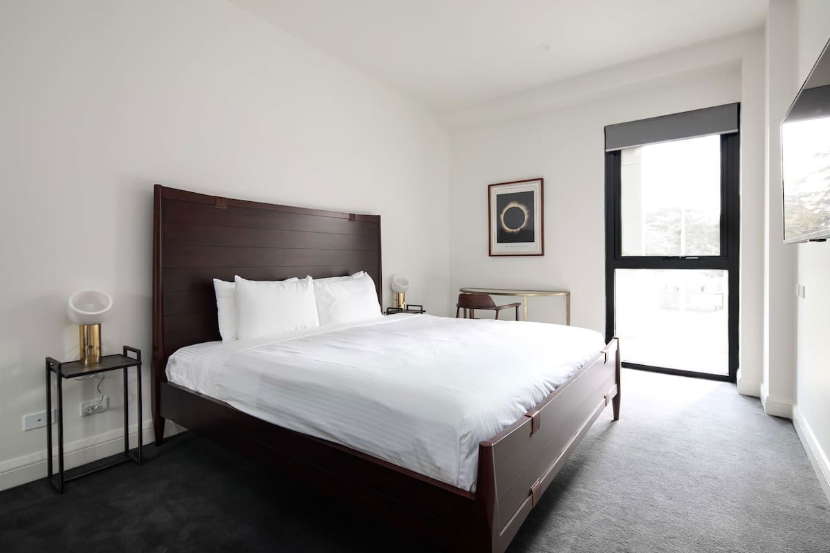 Una habitación de hotel moderna con una cama grande, mesitas de noche, un escritorio y una ventana.