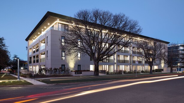 A modern multi-story building with a flat roof, large windows, and a well-lit facade. - Knightsbridge Canberra (Kingston)