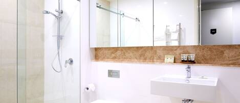 A modern bathroom with a glass-enclosed shower, a white sink, and a toilet.
