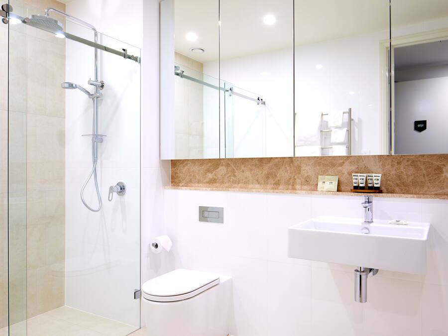 A modern bathroom with a glass-enclosed shower, a white sink, and a toilet.