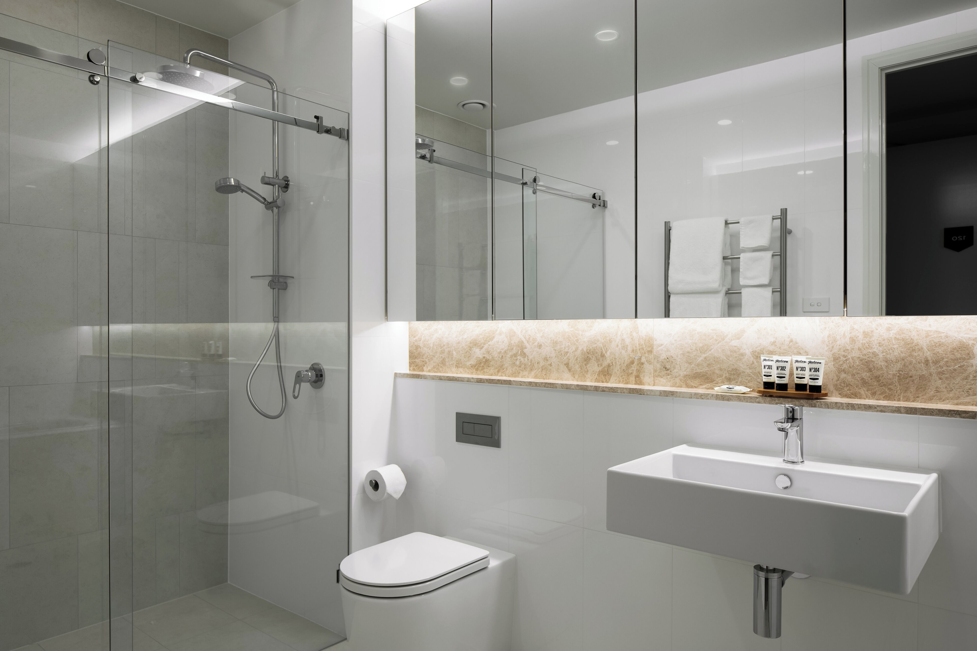 Une salle de bain moderne avec une douche à parois de verre, un lavabo blanc et des toilettes.