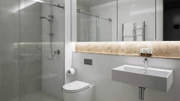 Une salle de bain moderne avec une douche à parois de verre, un lavabo blanc et des toilettes.